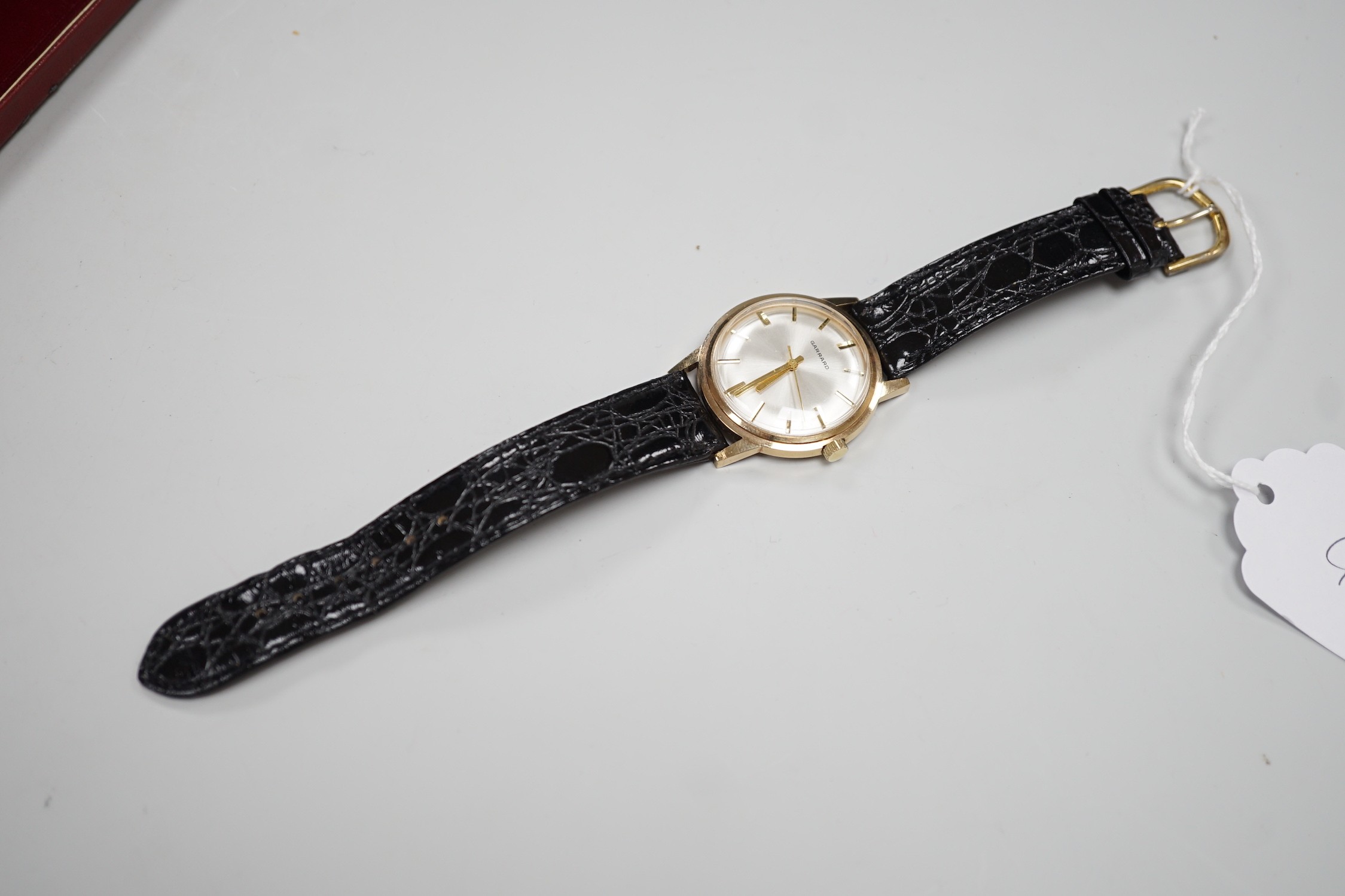 A gentleman's 1970's yellow metal Garrard manual wind wrist watch, with case back inscription, on a leather strap, case diameter 35mm, in Garrards box.